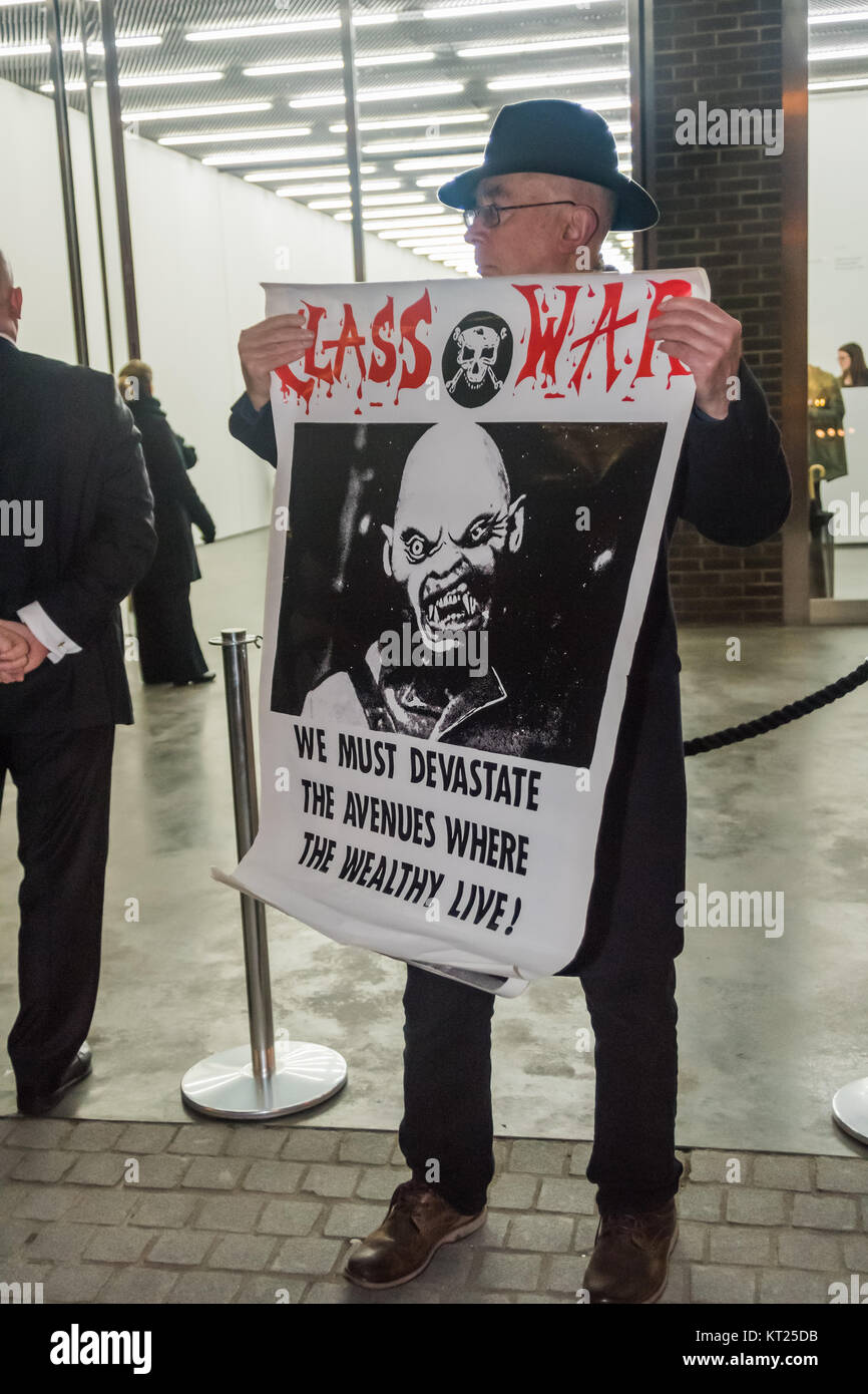 Ian Bone of Class War holdws a poster with the Lucy Parsons quotation 'We must devastate the avenues where the wealthy live!' outside the Gilbert & George show in Bermondsey. Stock Photo