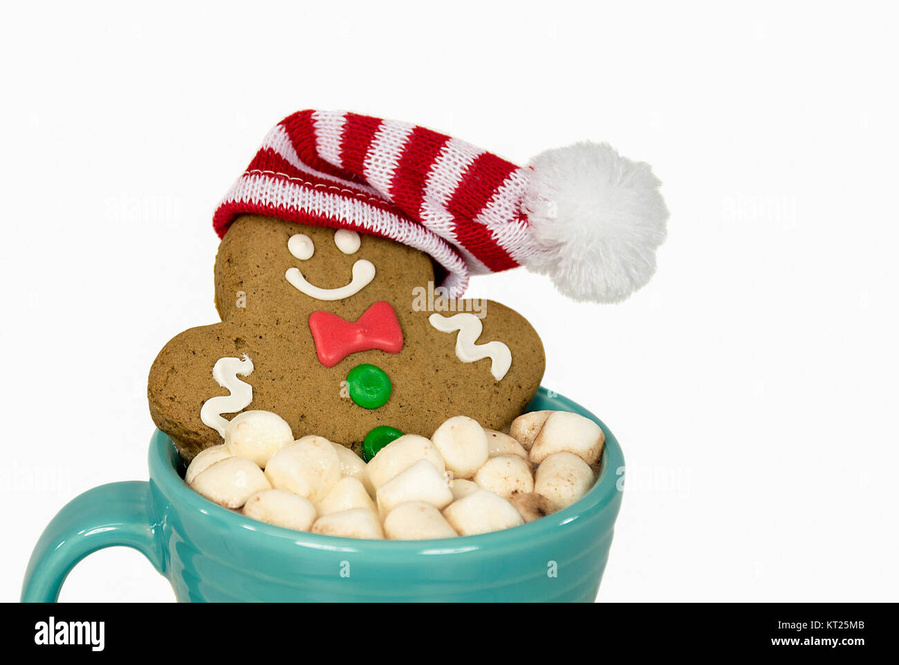 turquoise mug with gingerbread man wearing striped stocking cap in hot cocoa drink with marshmallows Stock Photo