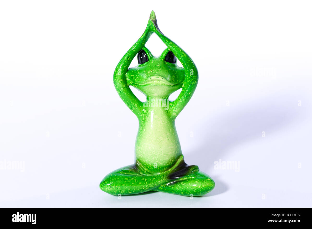 Close up of green frog figure doing yoga meditation Stock Photo