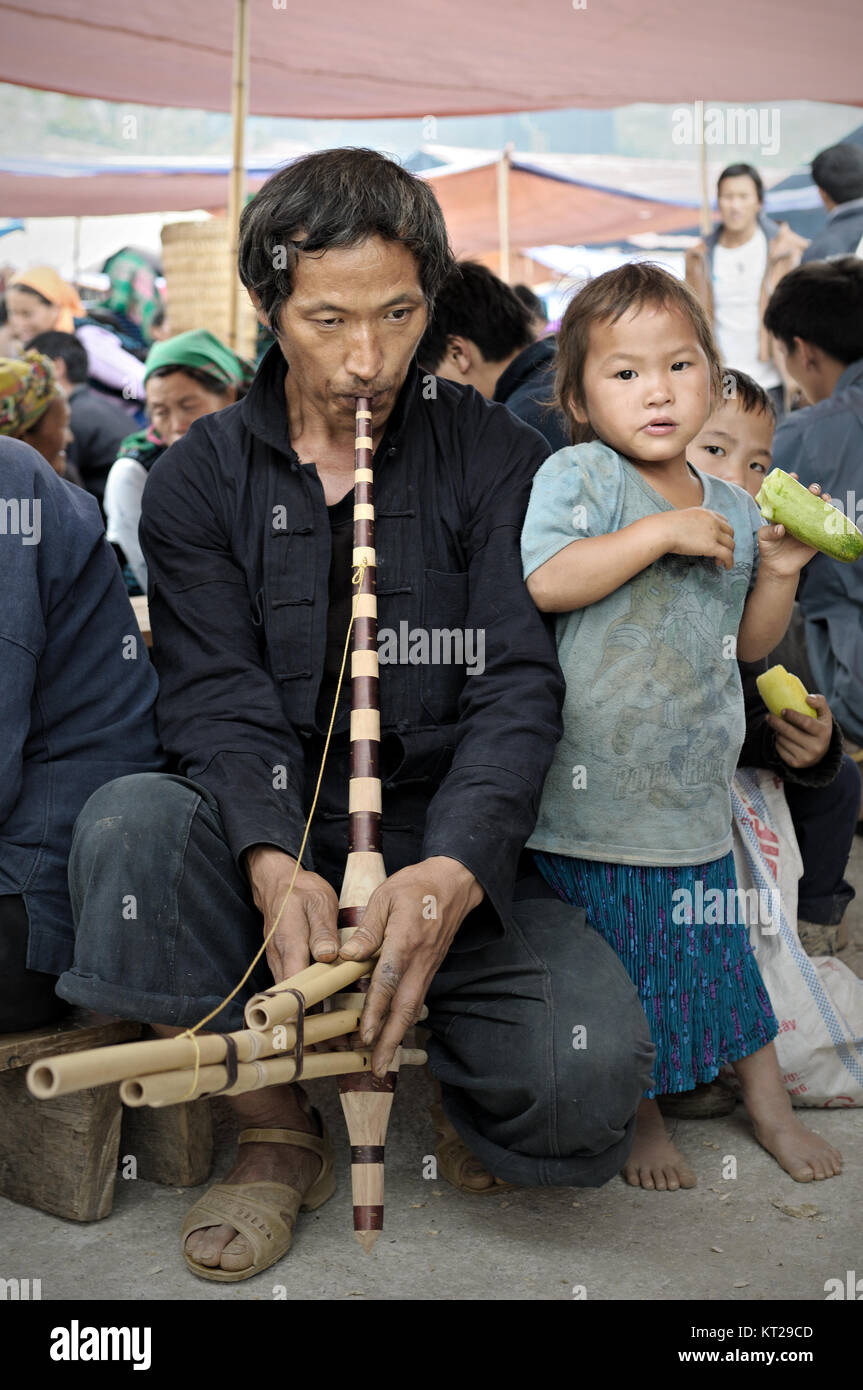Man playing a musical instrument (mouth organ called khene) in Meo Vac market, Ha Giang Province, north Vietnam Stock Photo