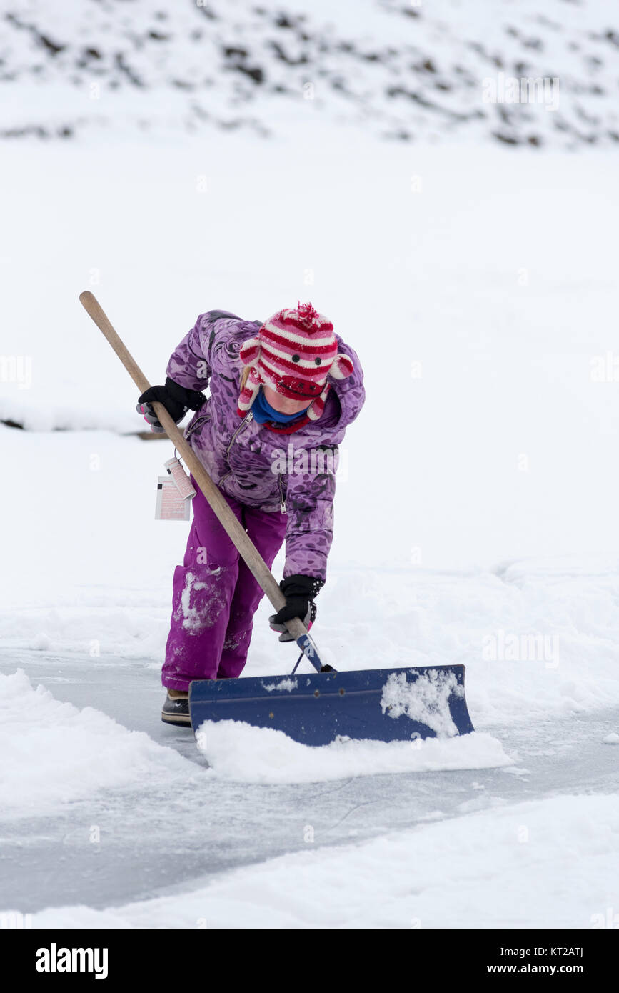 Girl shoveling snow on Kinney Lake in Northeast Oregon. Stock Photo