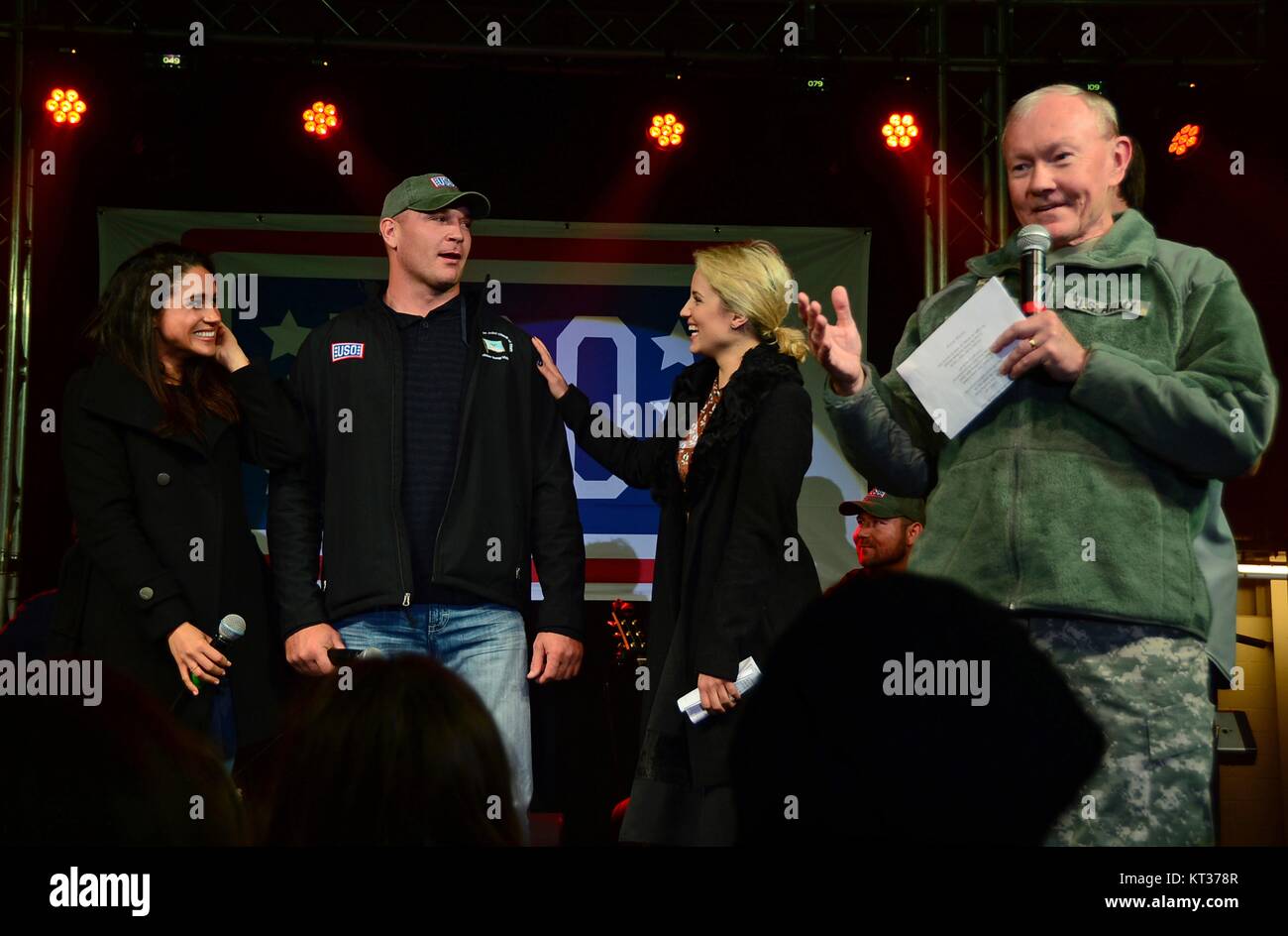 U.S. Chairman of the Joint Chiefs Gen. Martin Dempsey, right, addresses troops during the USO Holiday Troop Visit at Royal Air Force Mildenhall December 10, 2014 in Mildenhall, England. Standing with the General are (L to R): Actress Meghan Markle, former Chicago Bears linebacker Brian Urlacher, and actress Dianna Agron. Stock Photo