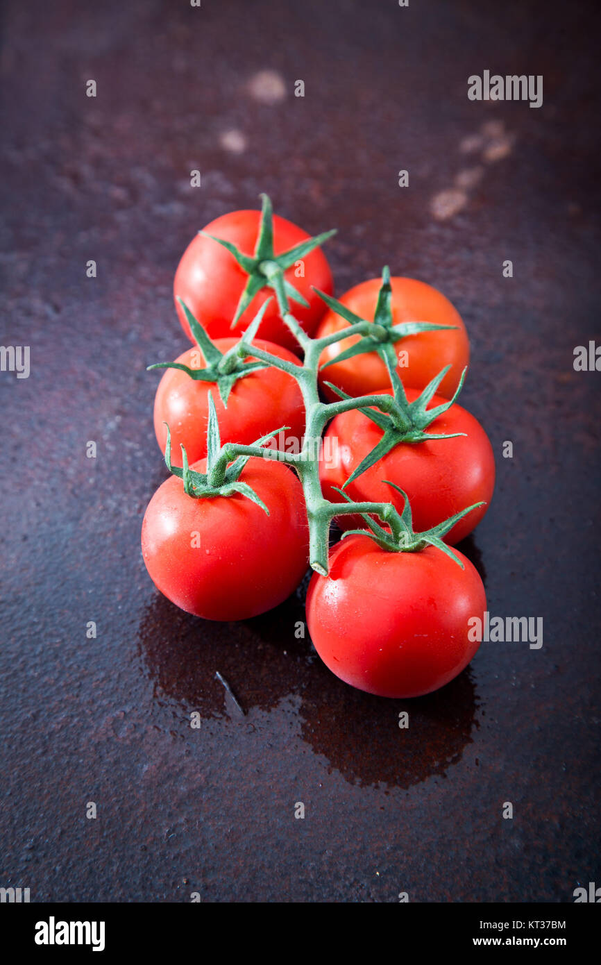 Fresh cherry tomatoes on a black background with spices. Top view with ...