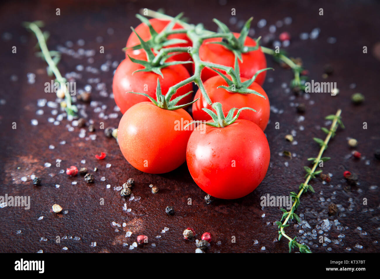 Fresh cherry tomatoes on a black background with spices. Top view with ...