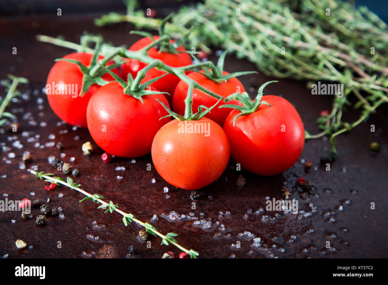 Fresh cherry tomatoes on a black background with spices. Top view with ...
