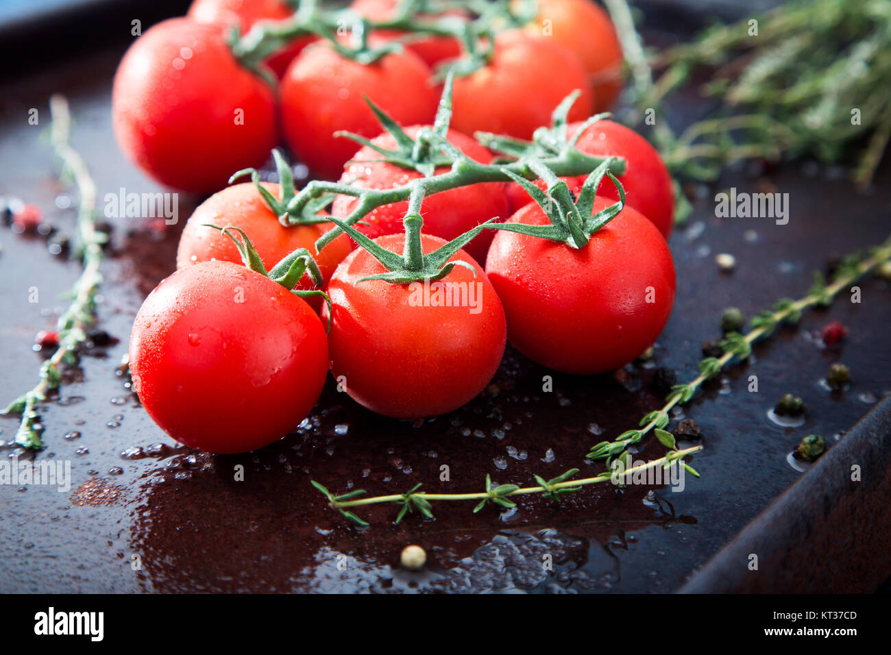 Fresh cherry tomatoes on a black background with spices. Top view with ...