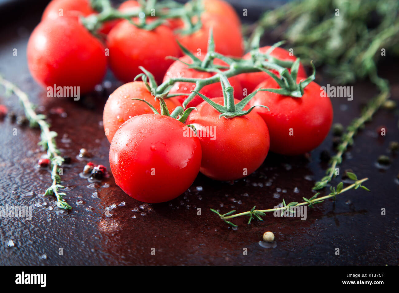 Fresh cherry tomatoes on a black background with spices. Top view with ...