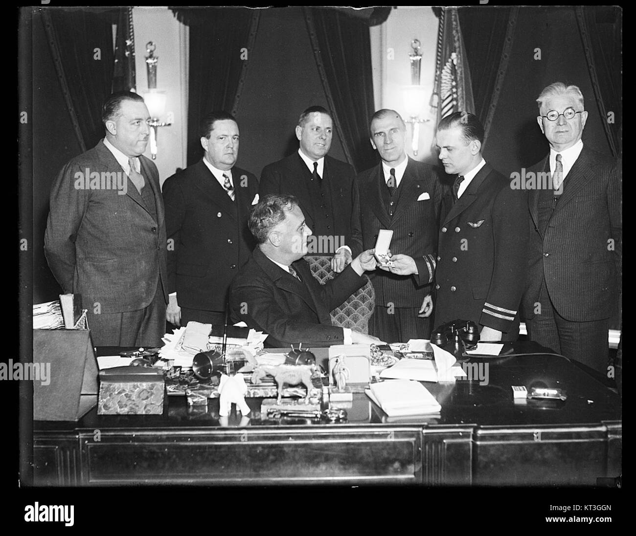 A black and white photograph from 1933 showing President Franklin D. Roosevelt seated at the Hoover desk in the Oval Office, reflecting the presidential workspace of that time. Stock Photo
