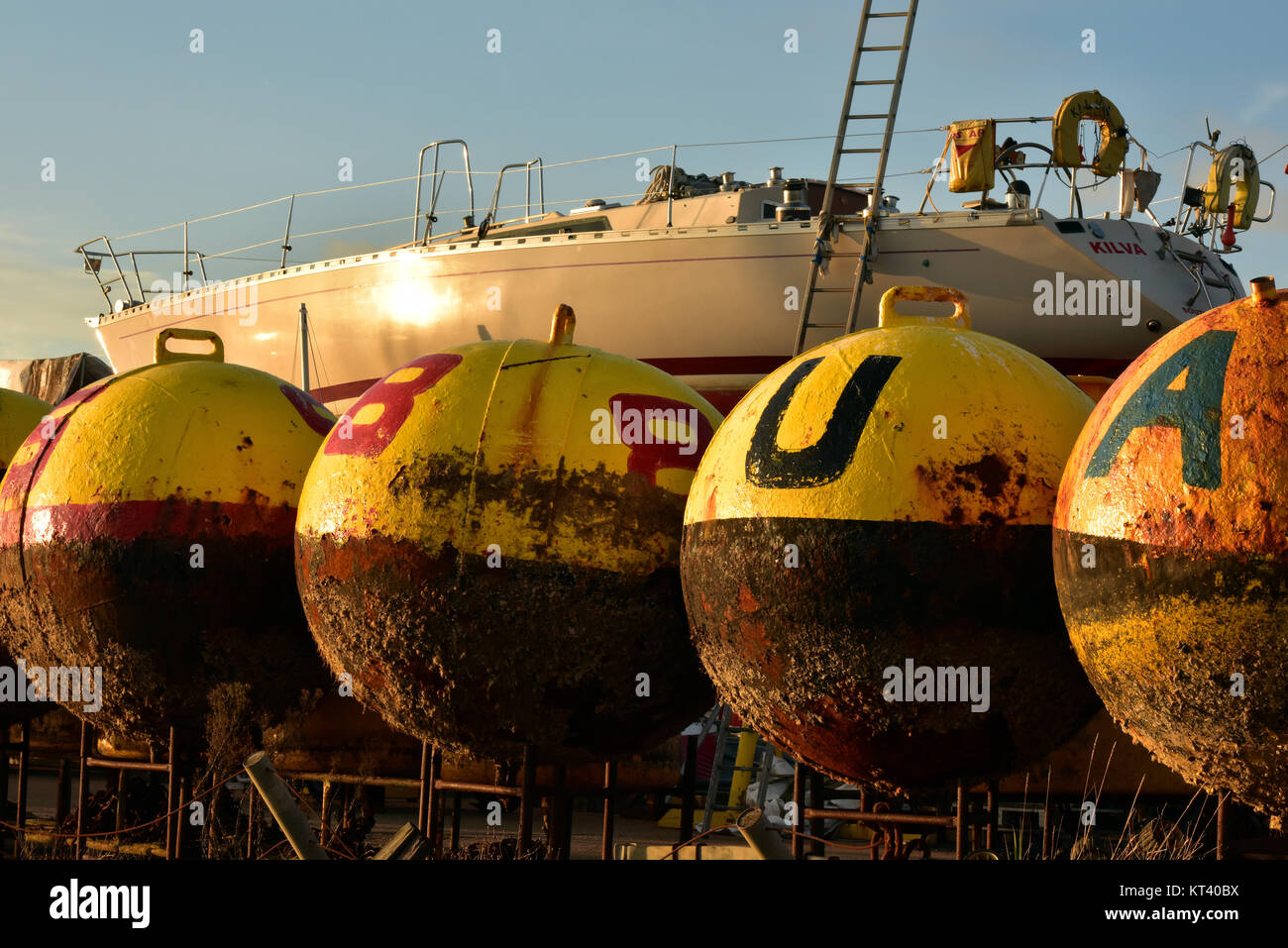 Rusty Yellow Buoys And A Sailing Yacht In A Traditional Boatyard On The