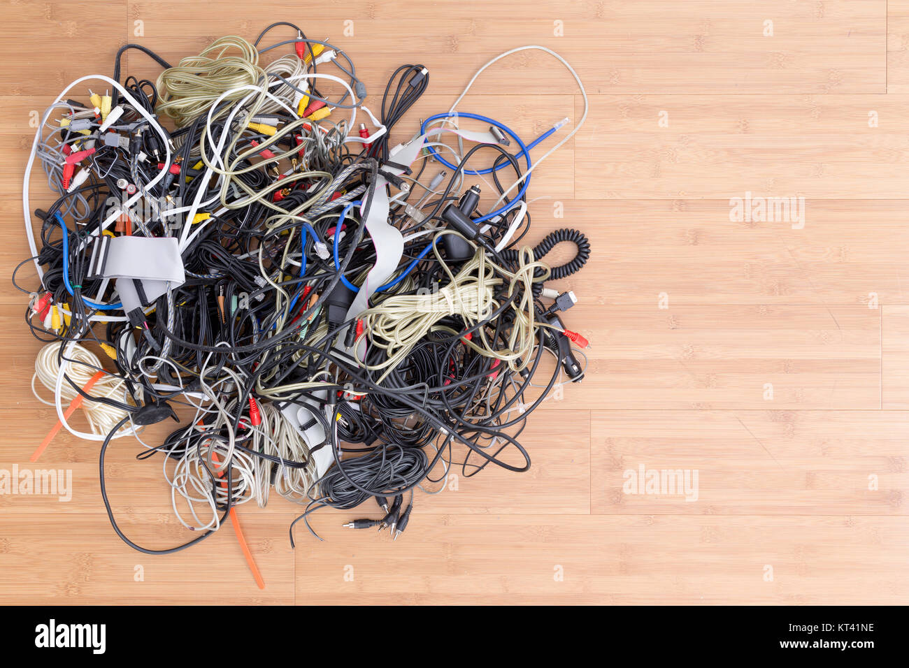 Messy tangle of old electric cords and connectors awaiting discard on a wooden surface with copy space in an overhead view Stock Photo