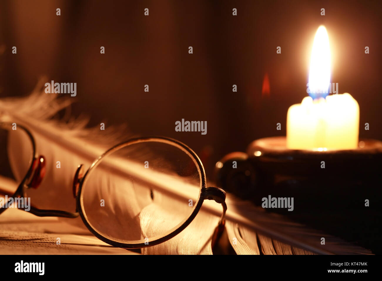 Vintage still life. Quill pen and lighting candle near old book Stock