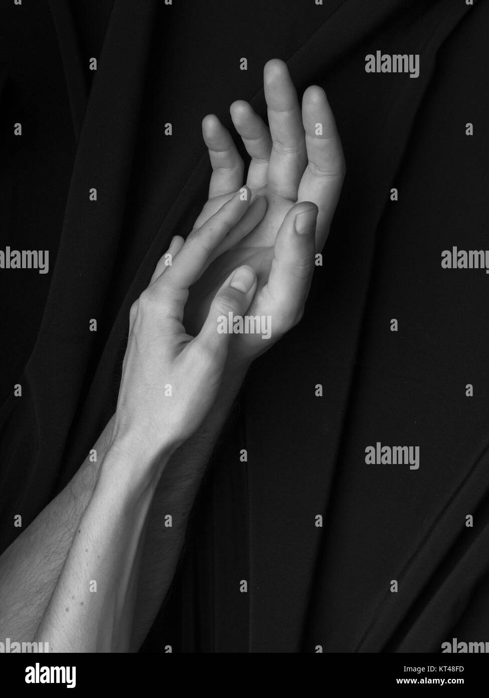 Black and white image, hands of man and woman tenderly touching each other on black background Stock Photo