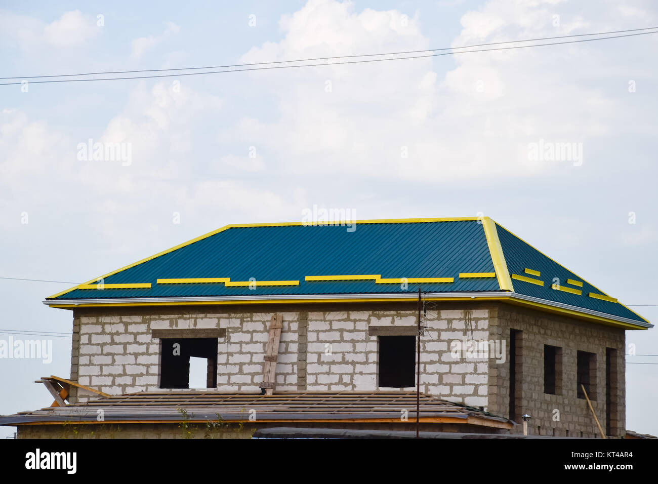 A house with a roof made of metal sheets. Yellow skating on the roof Stock Photo