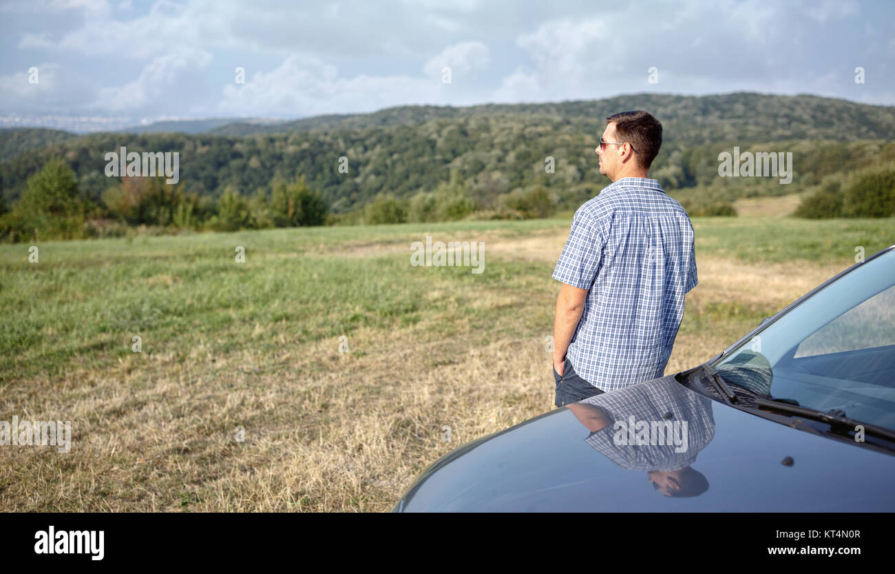 Road trip break after long drive. Young man enjoys sunset Stock Photo