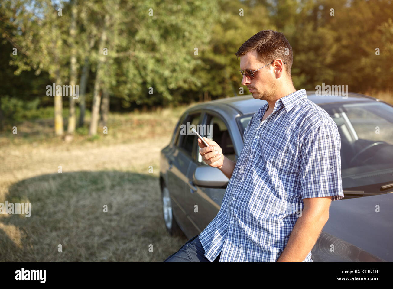 Road trip break after long drive- serious man using phone Stock Photo