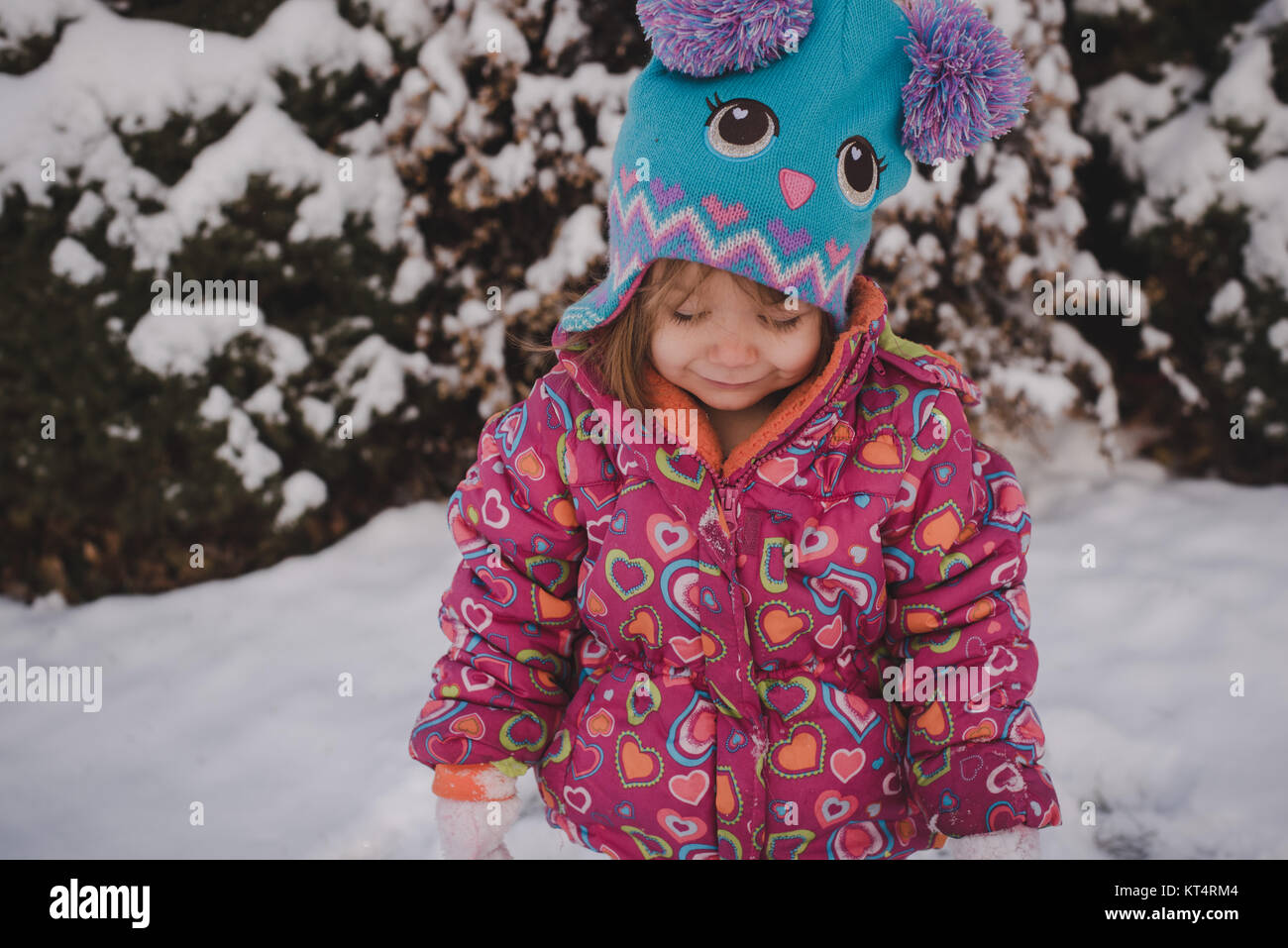 A toddler girl wearing a colorful coat plays in the snow Stock Photo ...