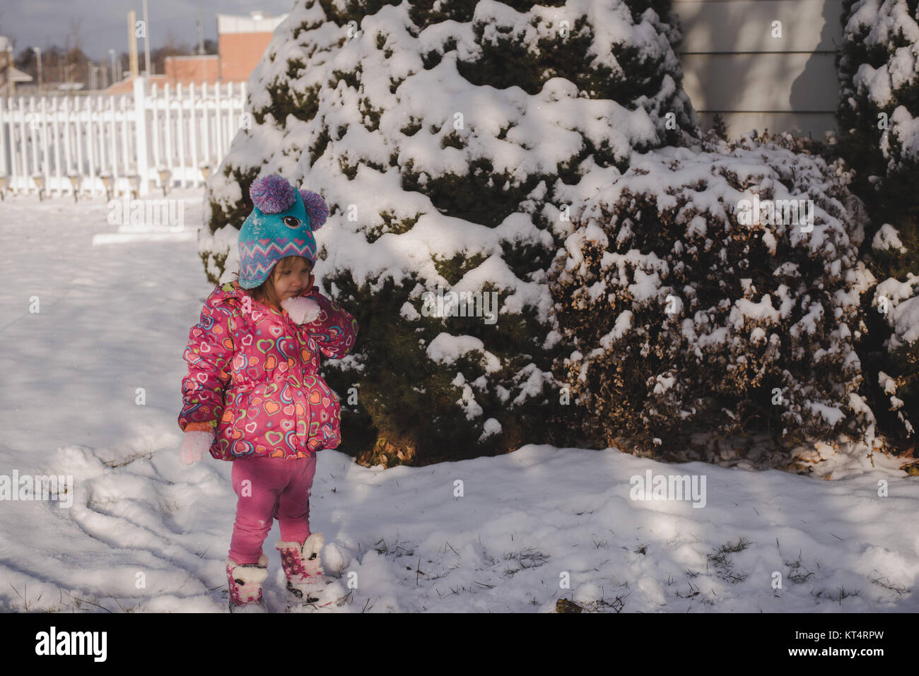 A toddler girl wearing a colorful coat plays in the snow Stock Photo ...