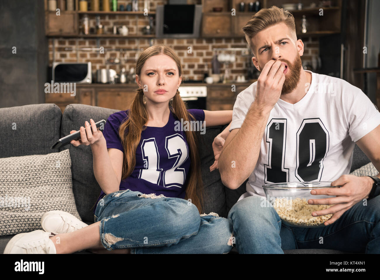 portrait of concentrated couple watching movie with popcorn at home Stock Photo