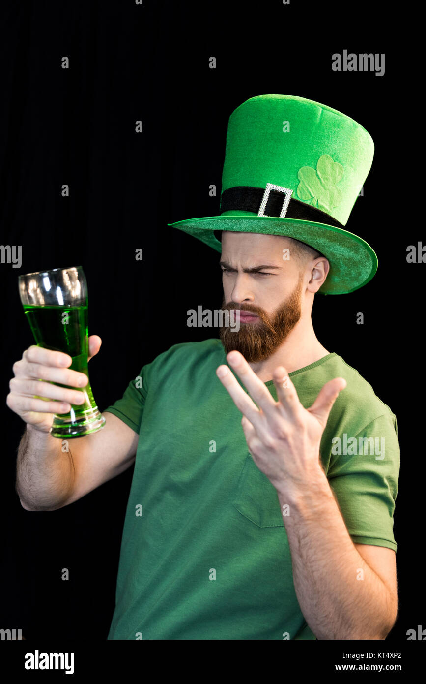 Portrait of upset man holding glass of beer on St.Patrick's day on black Stock Photo