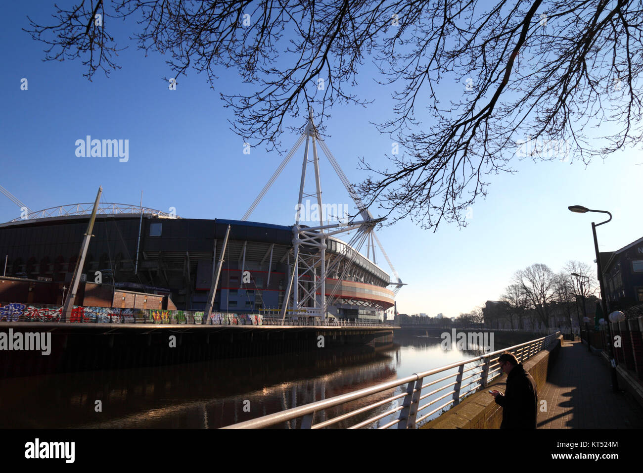View of Millennium / Principality Stadium, River Taff, and man using smartphone, Cardiff, South Glamorgan, Wales, United Kingdom Stock Photo