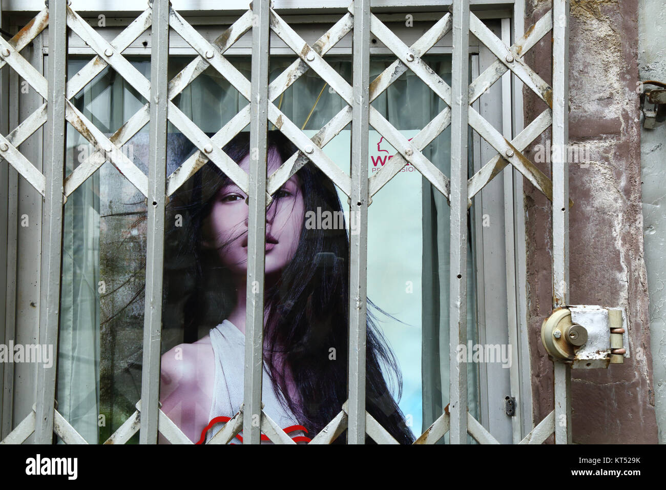 Advertising poster with face of beautiful female model behind security railings on beauty parlour entrance, La Paz, Bolivia Stock Photo