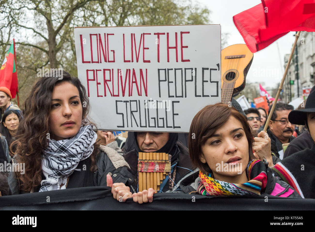 'Long Live the Peruvian People's Struggle poster behind people carrying the main banner in the in the Global Frontlines bloc which marched ahead of the main People's Climate March in London. Stock Photo