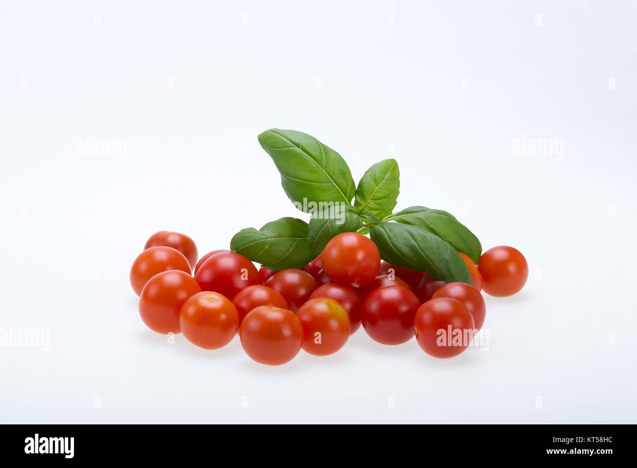 fresh cherry tomatoes with basil, on white background Stock Photo - Alamy
