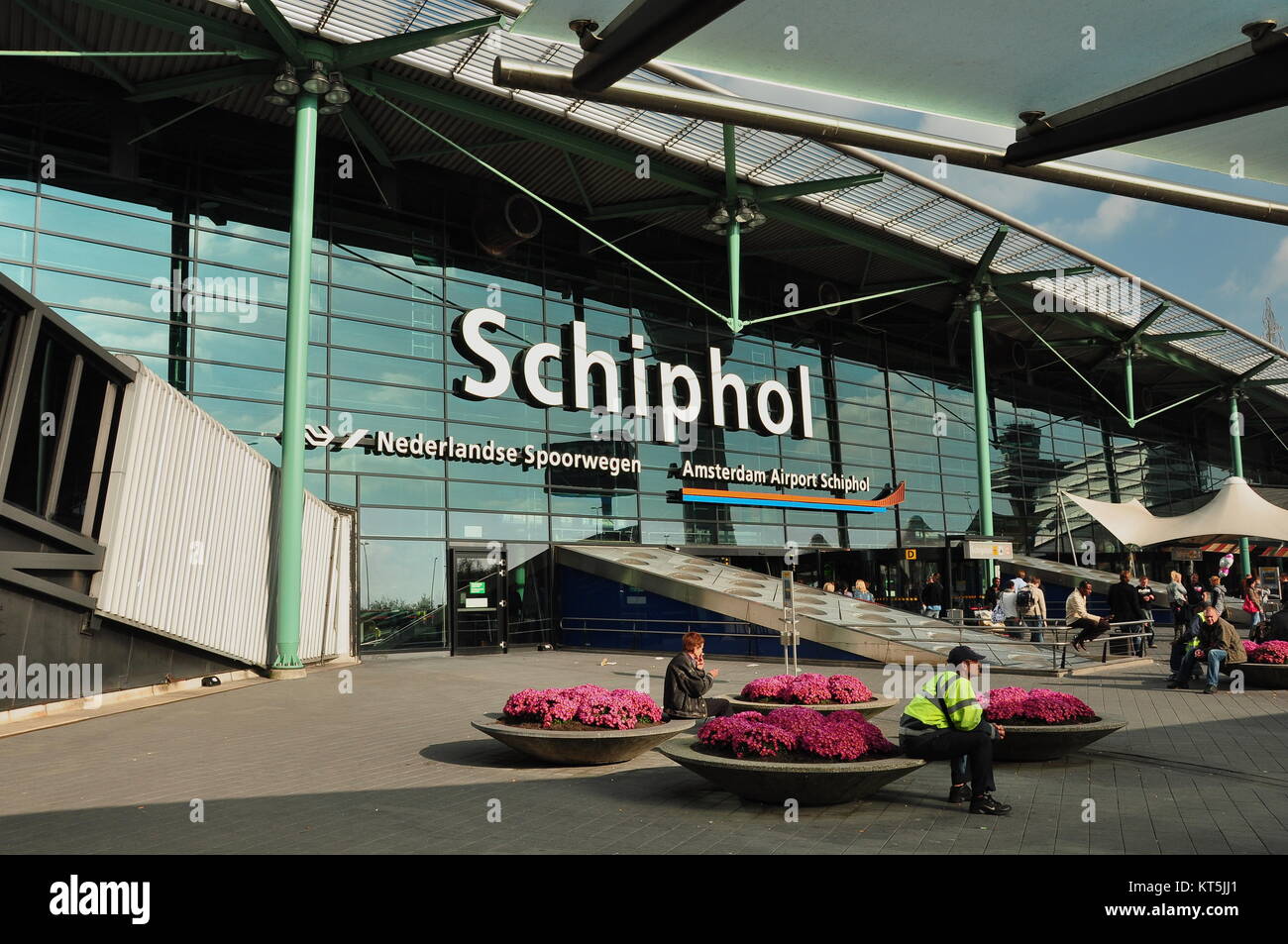 Schiphol airport entrance in Amsterdam Netherlands. People sitting outside Amsterdam's airport. Dutch airport in Amsterdam. Stock Photo