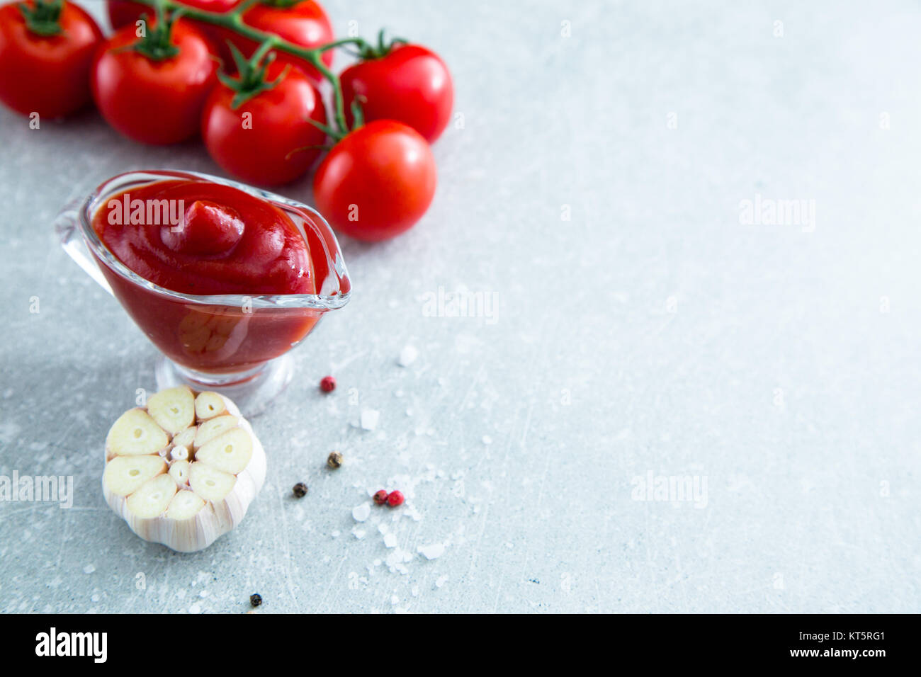 Tomato ketchup sauce with garlic, spices and herbs with cherry tomatoes in a glass bowl on stone