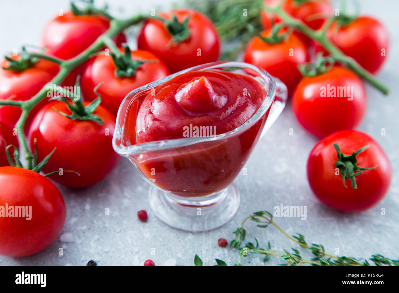 Tomato ketchup sauce with garlic, spices and herbs with cherry tomatoes in a glass bowl on stone
