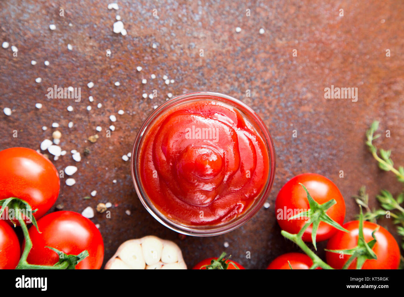 Tomato ketchup sauce with garlic, spices and herbs with cherry tomatoes in a glass bowl on stone