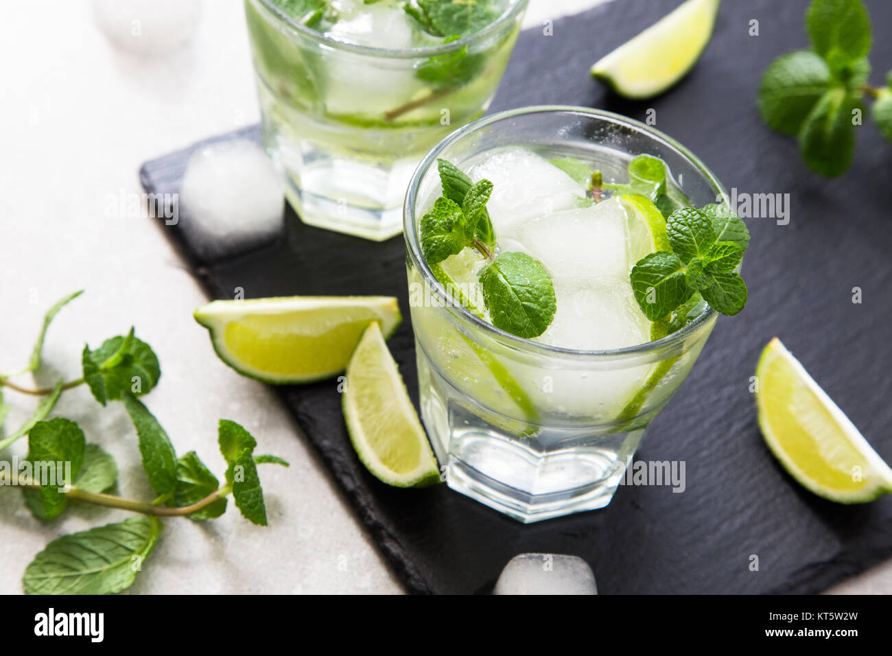Cold refreshing summer lemonade mojito in a glass on a slate board and stone background. Stock Photo