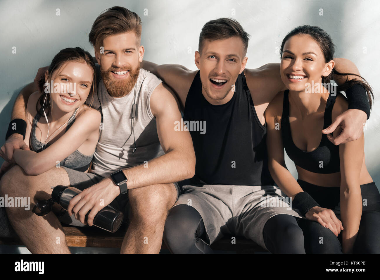 portrait of smiling sporty men and women sitting on bench in gym Stock ...