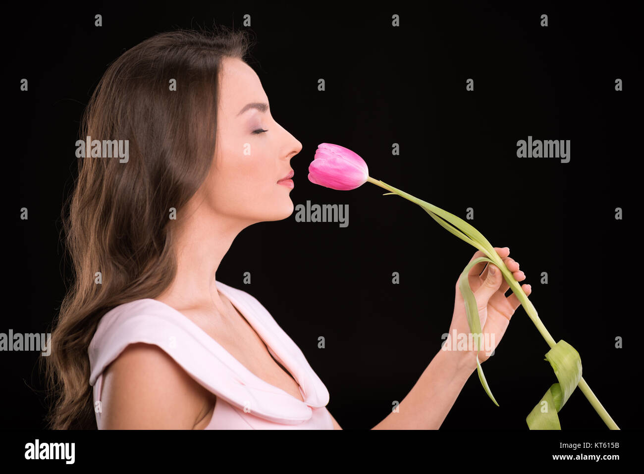 Side view of beautiful young woman with closed eyes smelling tulip ...