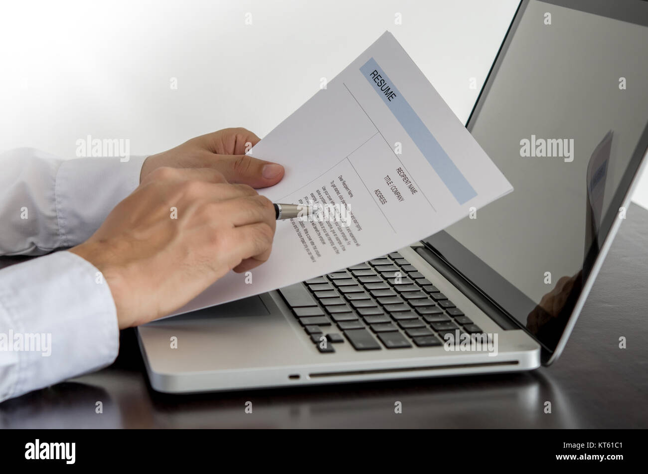 job seeker review his resume on his desk with pen and computer laptop. Stock Photo