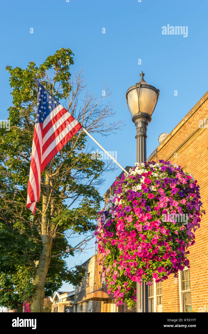 Beautiful petunia baskets adorn the lampposts in Downtown Austin, Minnesota, with American Flag Stock Photo