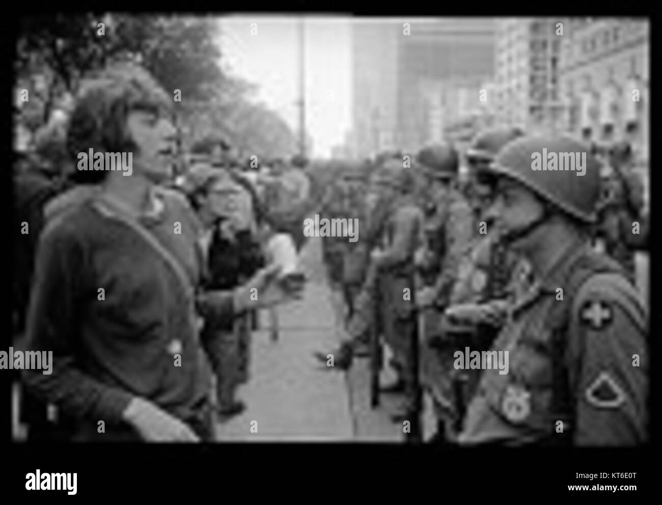Young  hippie  standing in front of a row of National Guard soldiers  across the street from the Hilton Hotel at Grant Park  at the Democratic National Convention in Chicago  August 26  1968 Stock Photo