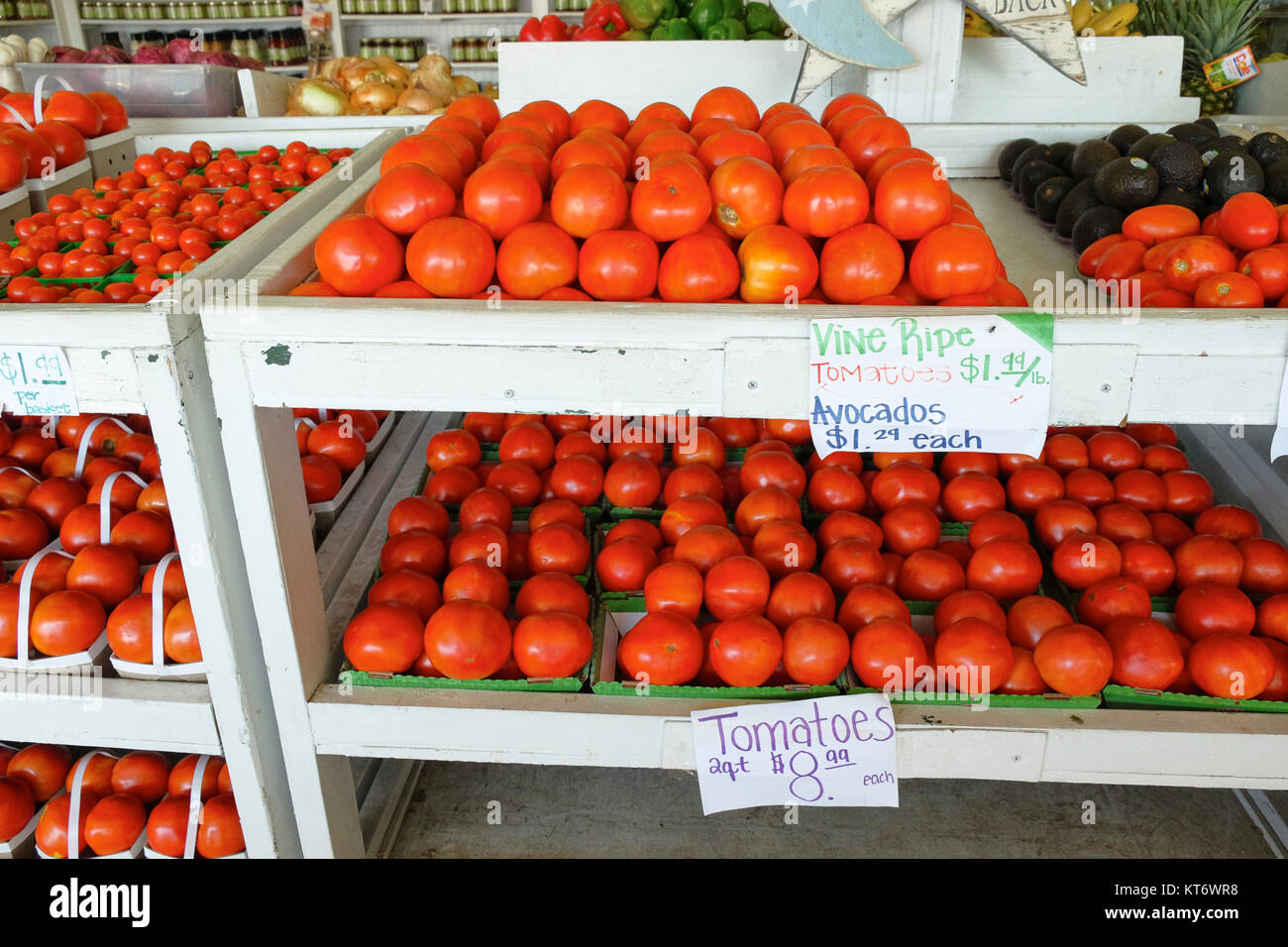 Farmer's market or produce market or stand with beefsteak, roma and cherry tomatoes for sale along with avocados and other fruits and vegetables. Stock Photo