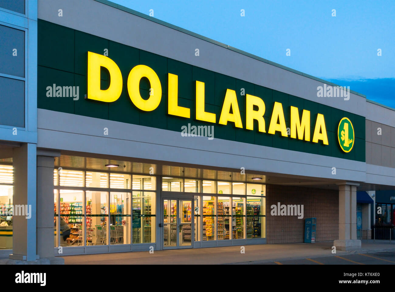 A Dollarama Inc. sign and storefront illuminated at dusk. Stock Photo