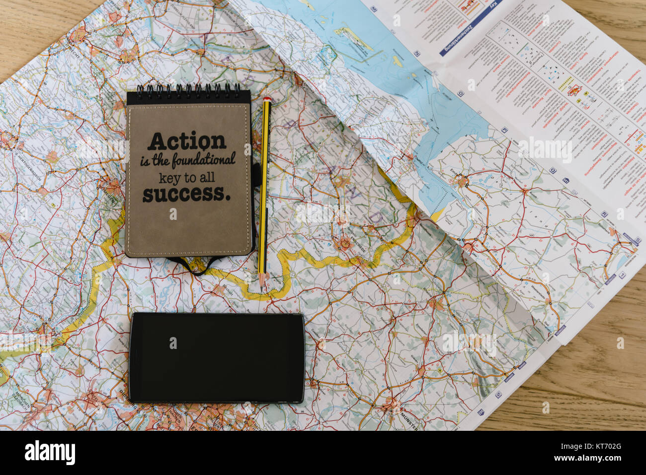 Lay flat of map, notebook with motivational quote, phone and pencil ...