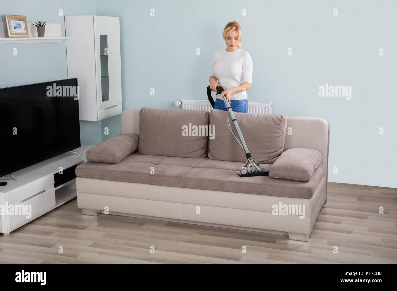 Woman Cleaning Sofa With Vacuum Cleaner Stock Photo Alamy