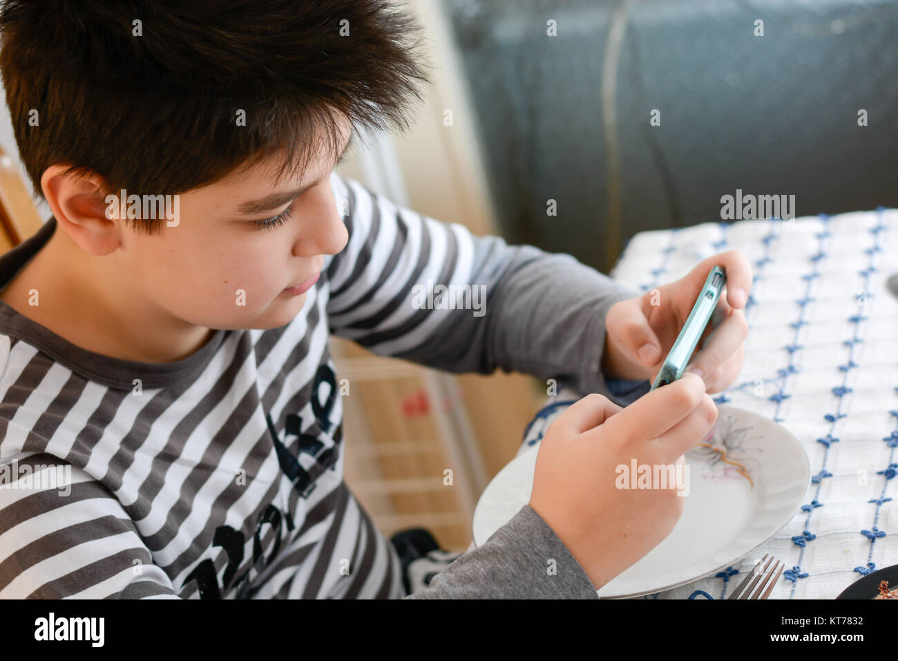 Boy playing with his phone during lunch Stock Photo Alamy