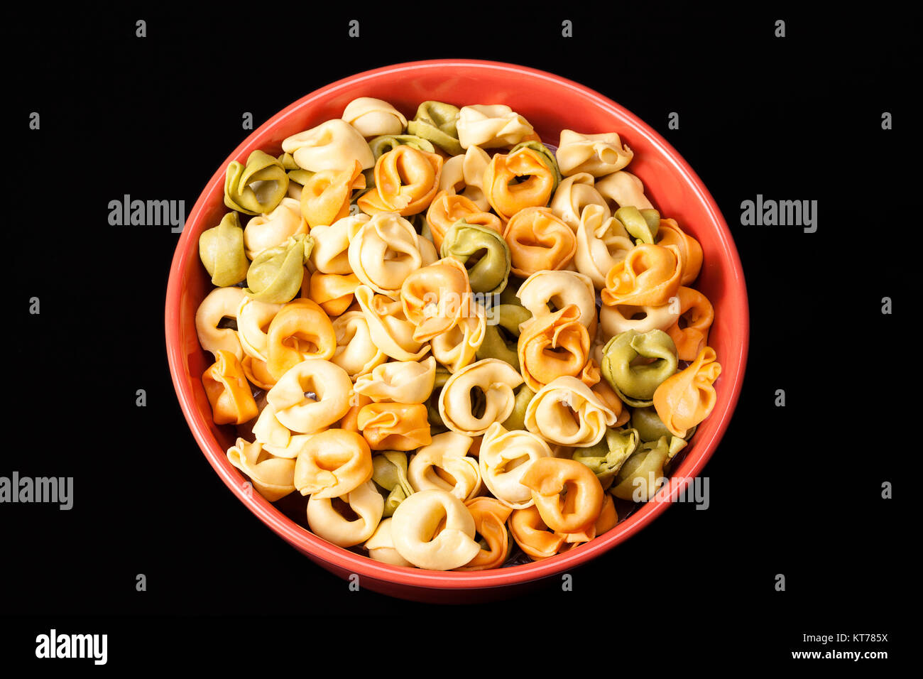 Colored tortellini, ring-shaped pasta in red bowl Stock Photo