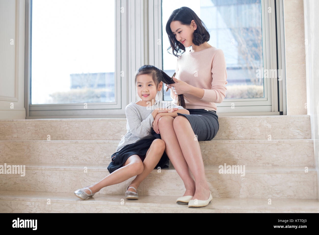 Young mother combing daughter's hair in the living room Stock Photo