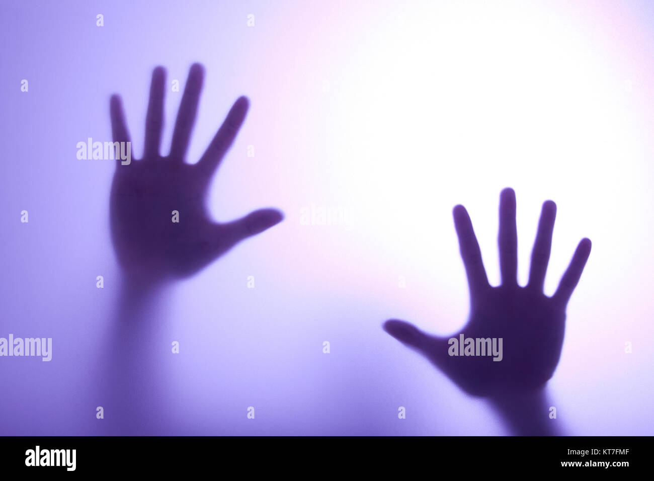 blurry hands reaching out and touching glass with Blue light Stock Photo