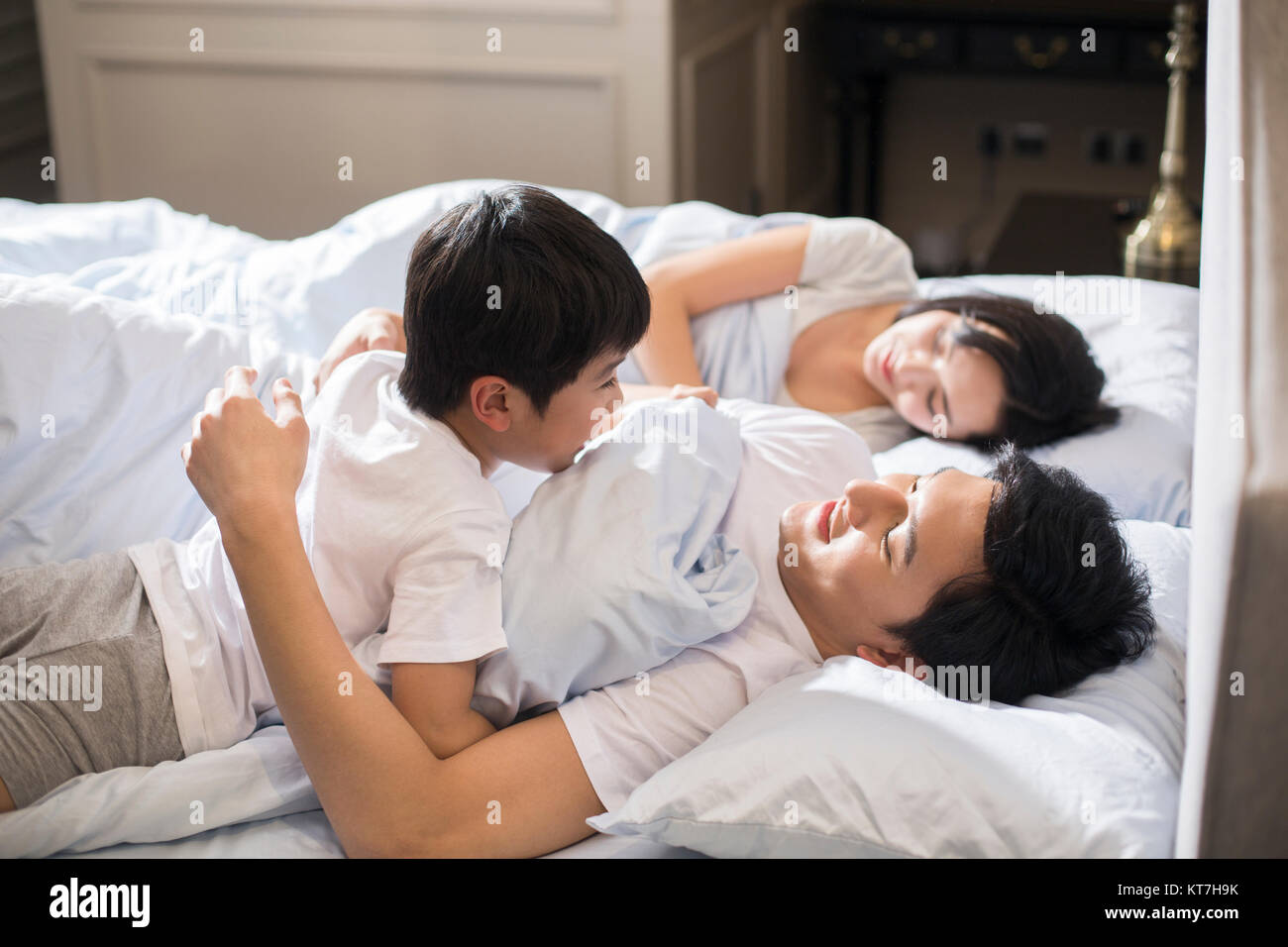 Cheerful boy waking up his parents in bedroom Stock Photo - Alamy