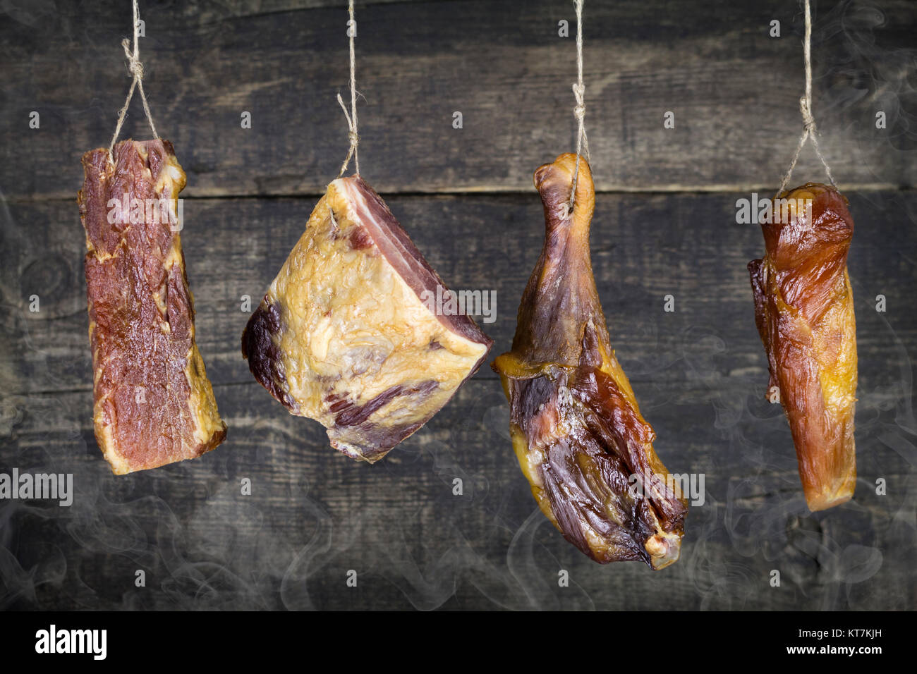 Smoked Meat Hanging on the Rope Against Wooden Background Stock Photo