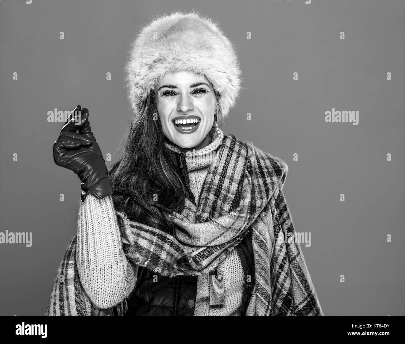 Winter things. Portrait of smiling trendy woman in fur hat isolated on cold blue snapping fingers Stock Photo