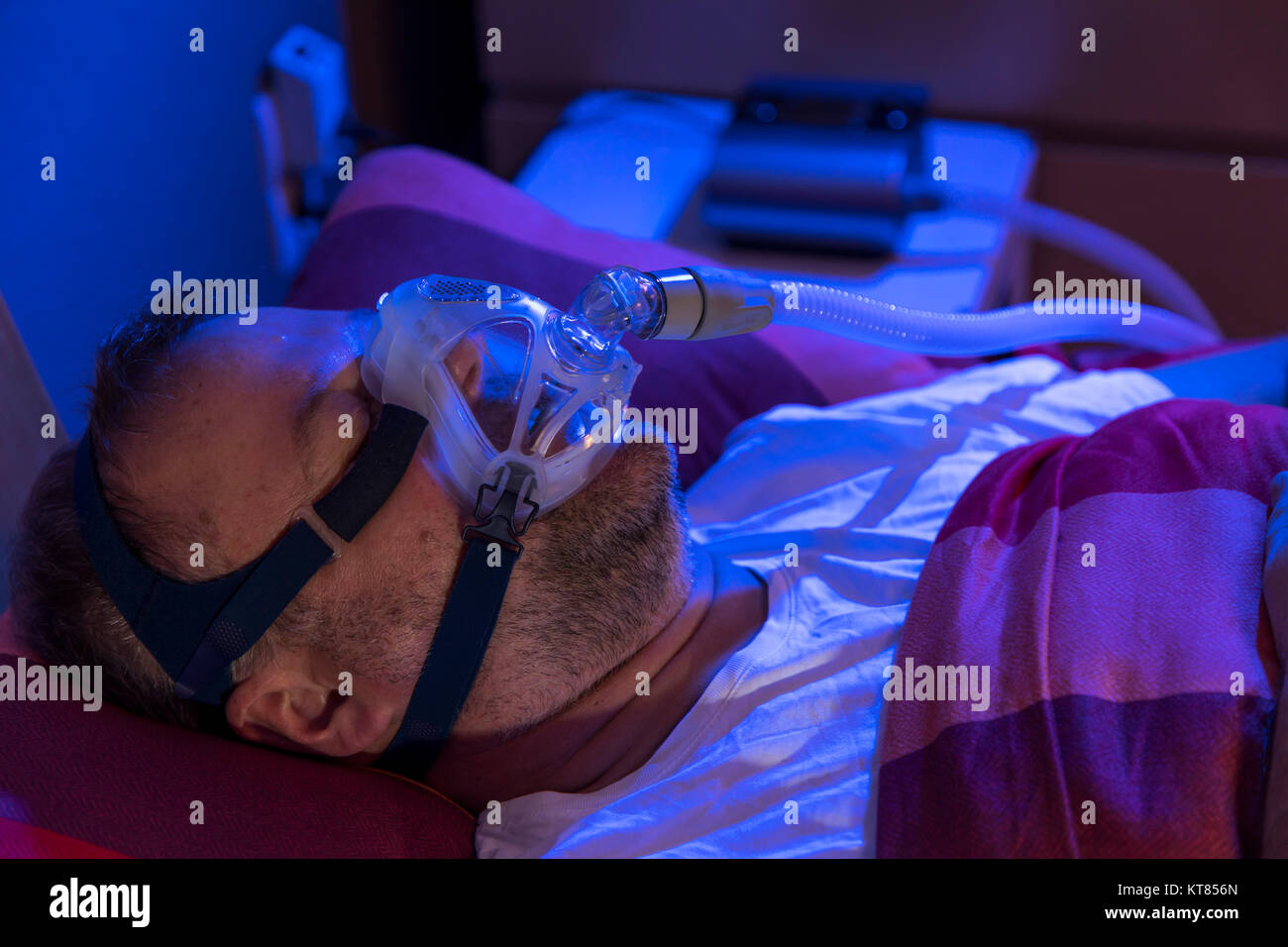 A man with sleep apnea syndrome, wears a CPAP mask while sleeping, breathing mask that presses