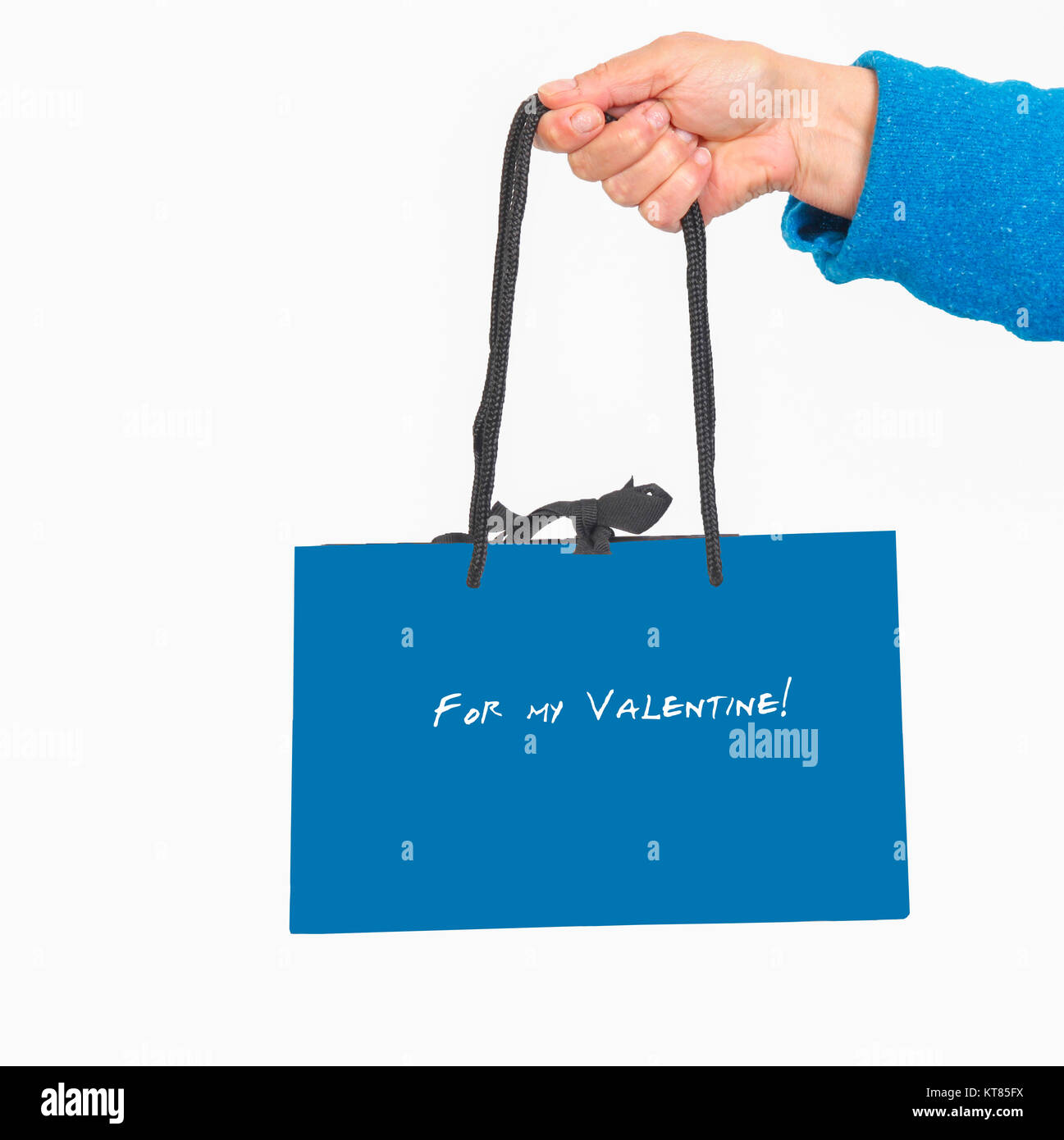 Hand in blue sweater holding blue bag with Valentine text Stock Photo